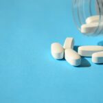 Frasco de pastillas blancas sobre fondo celeste