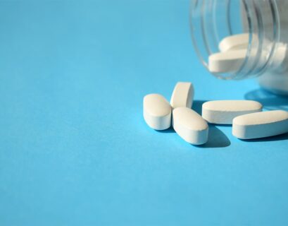 Frasco de pastillas blancas sobre fondo celeste
