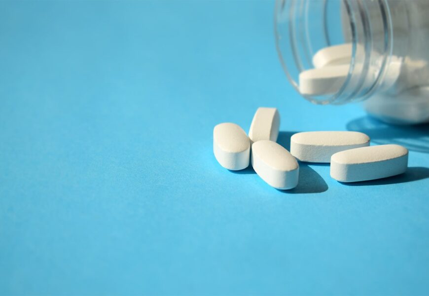 Frasco de pastillas blancas sobre fondo celeste