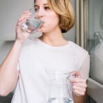 Mujer tomando agua cerca de una ventana
