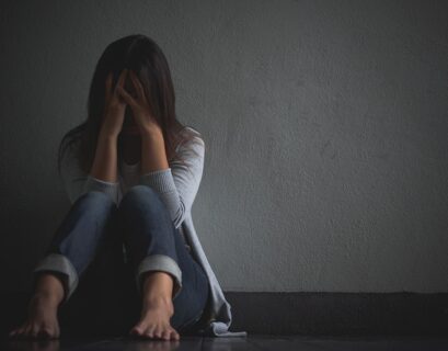 Mujer deprimida sentada en el piso y agarrando su cabeza