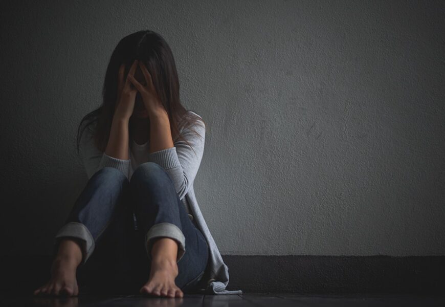 Mujer deprimida sentada en el piso y agarrando su cabeza