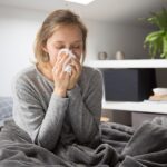 Mujer con enfermedad en su cama sonandose la nariz