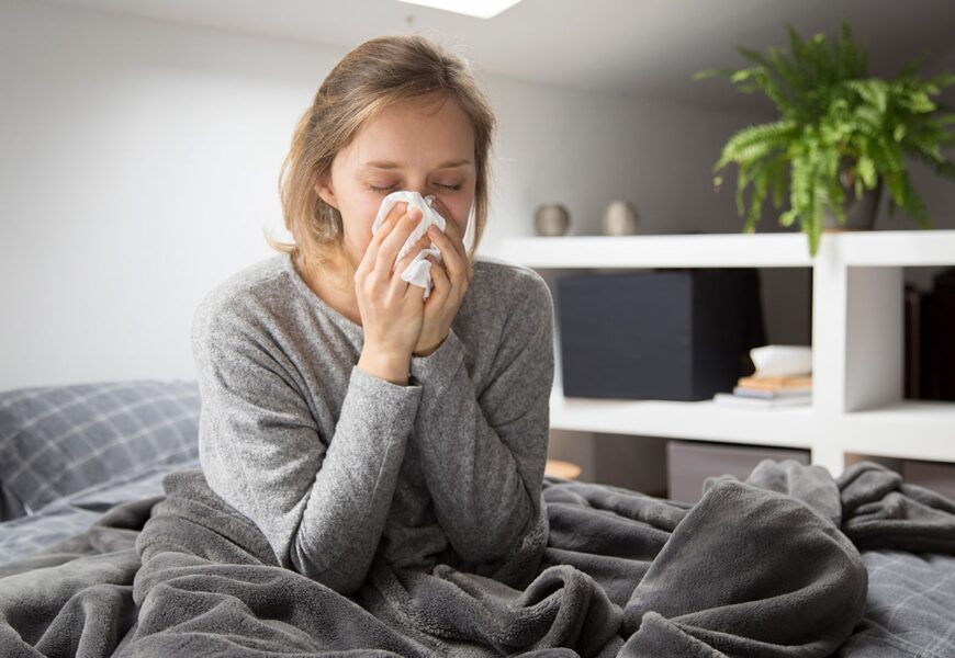 Mujer con enfermedad en su cama sonandose la nariz