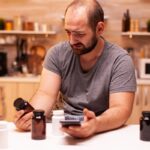 Hombre con dolor de cabeza sosteniendo un frasco de analgésicos