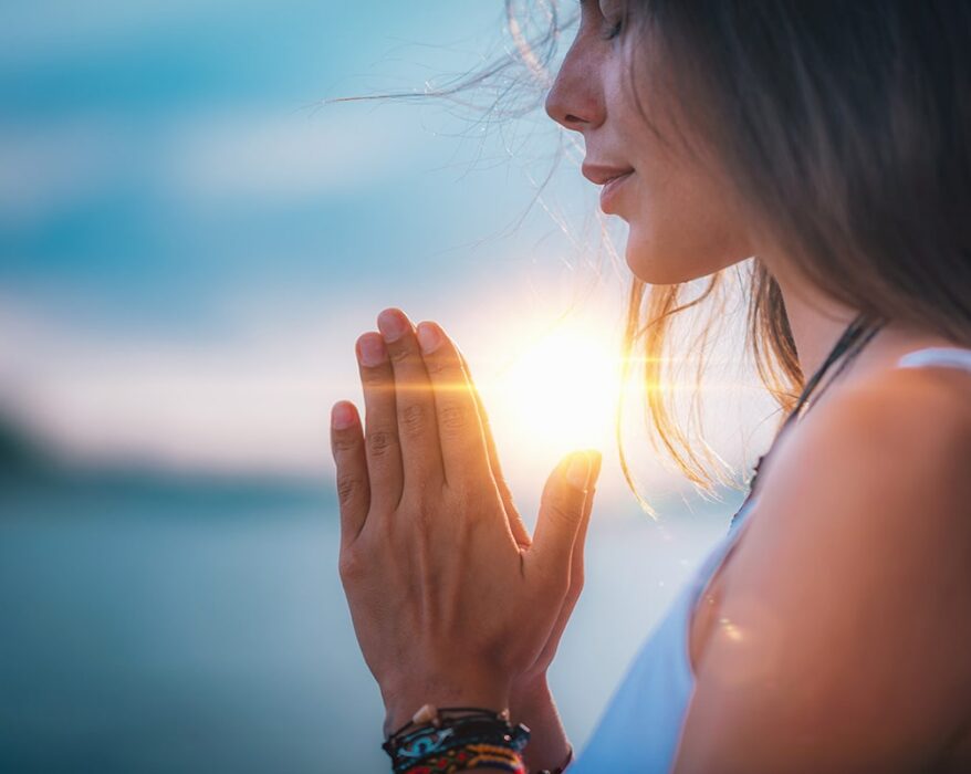 Mujer meditando con sus manos en posición de oración