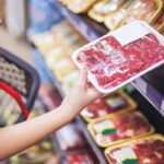 Mujer agarrando carne envuelta en el supermercado