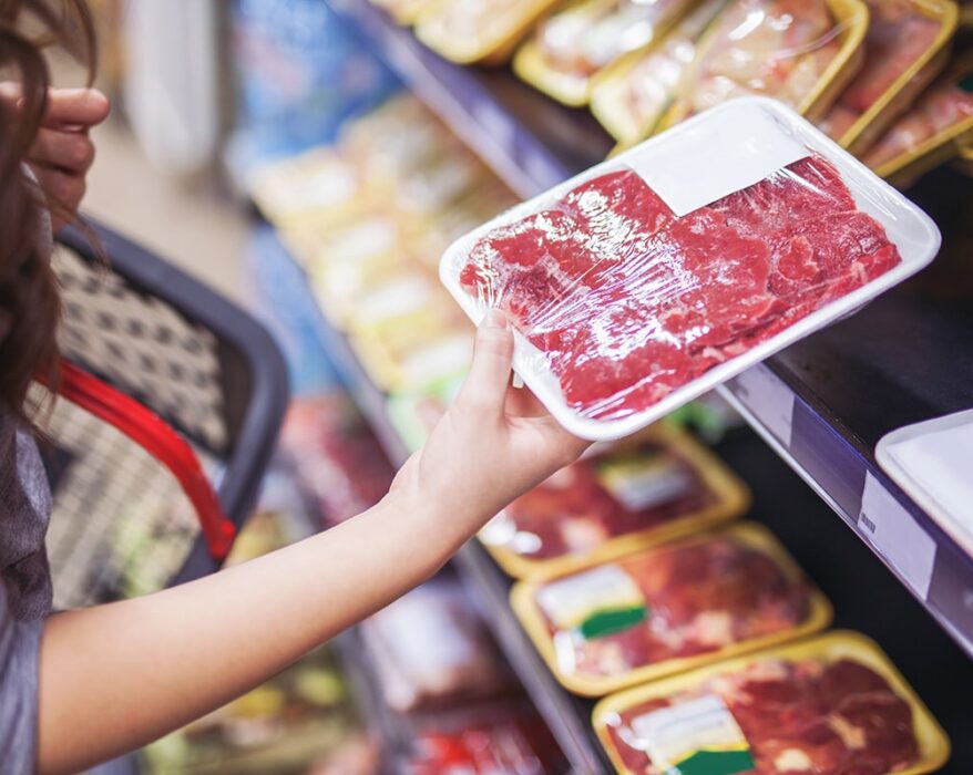 Mujer agarrando carne envuelta en el supermercado