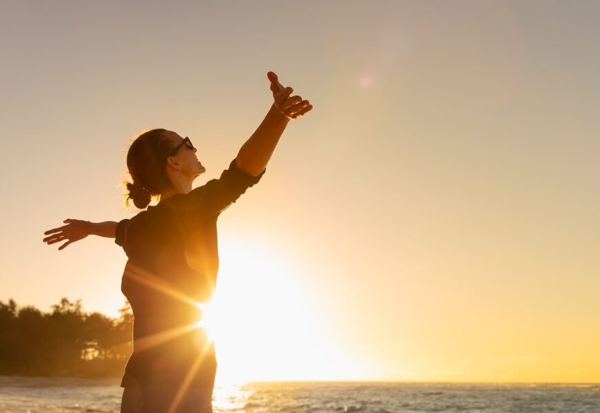 mujer contenta en la playa mirando el cielo