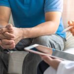 Hombre sentado con su mécico con una tableta