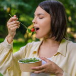 Mujer comiendo una ensalada en la naturaleza