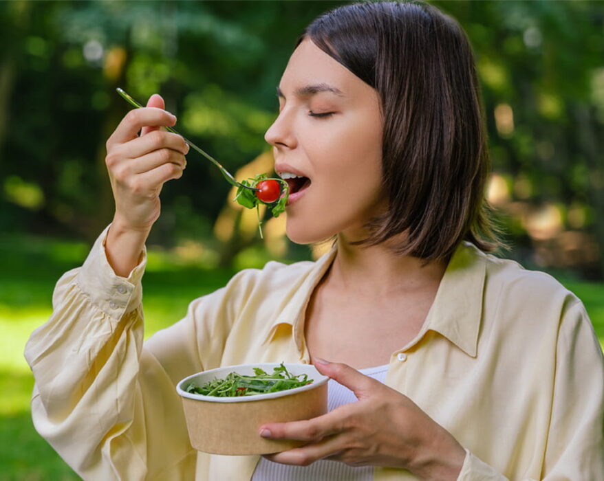 Mujer comiendo una ensalada en la naturaleza