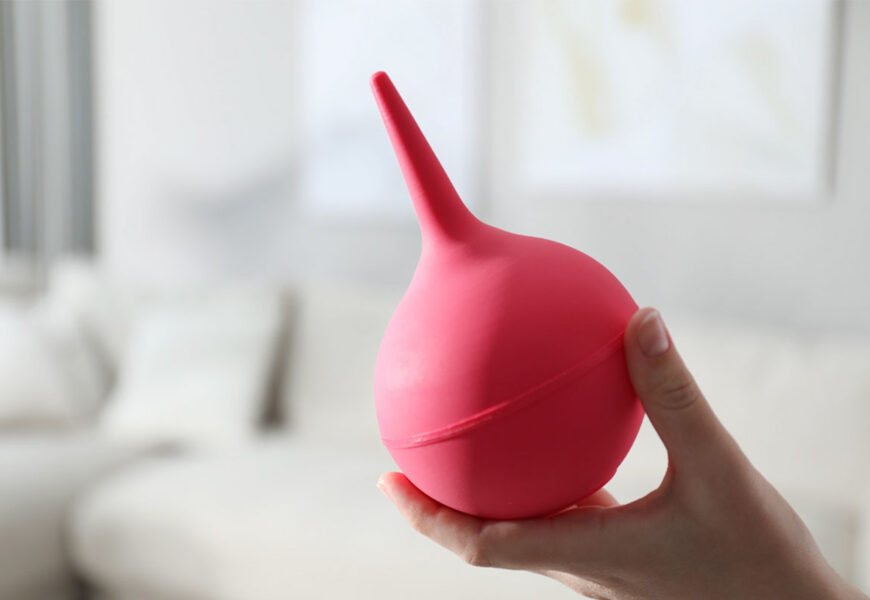 Mano sosteniendo pera de goma para hacer enemas