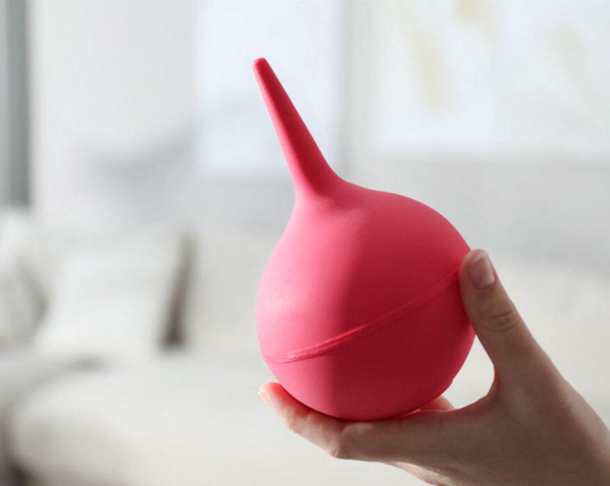 Mano sosteniendo pera de goma para hacer enemas